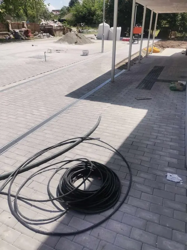 Fedett beálló térkövezése sötét sávos téglakővel és beépített folyókával